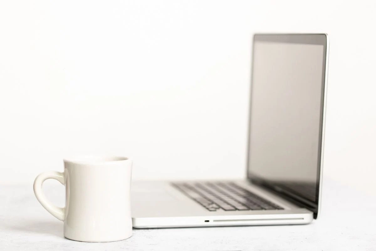 open laptop and white coffee mug